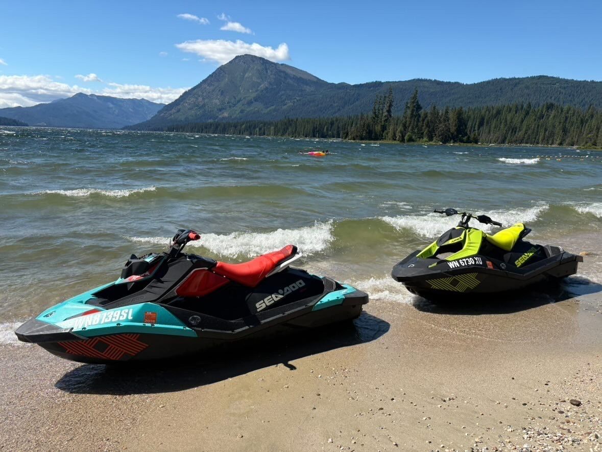 Teal and neon green Sea-Doo jet skis parked on the sand