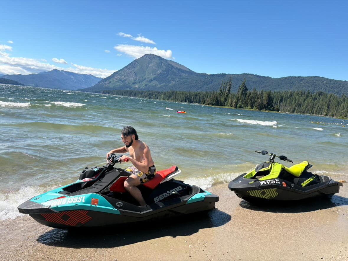 Rider smiling on a teal Sea-Doo Spark Trixx at the shoreline